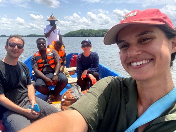 A corporate sustainability team on a field visit in Ghana rides in a boat across the Keta Lagoon